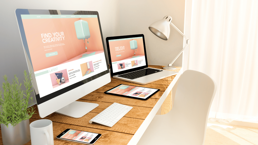 A desk holding a computer, a tablet, and a phone, all displaying a landing page on why you need a website as a creative