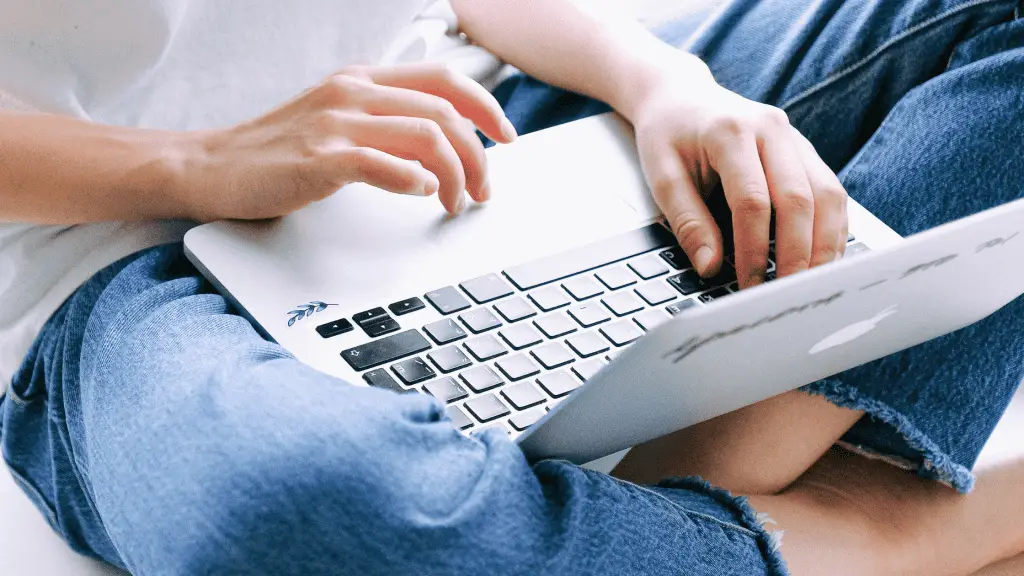 Woman sitting on the floor holding a macbook. She is a freelancer trying to get new clients.