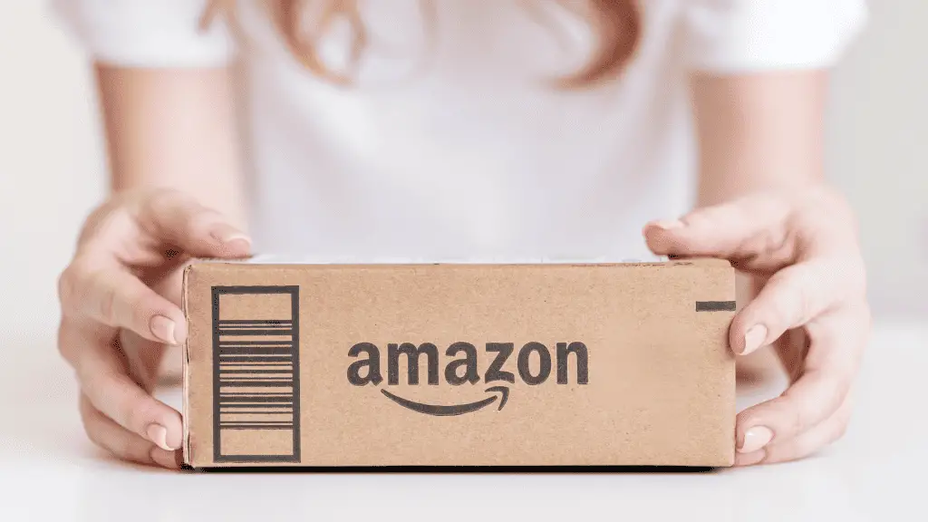 Woman in a white t-shirt holding an amazon box.